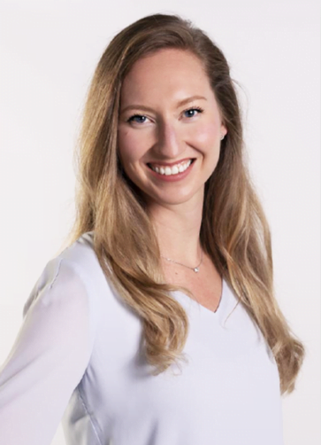 A woman with long, light brown hair smiles at the camera. She is wearing a light-colored blouse and has a natural, happy expression. The background is plain white.